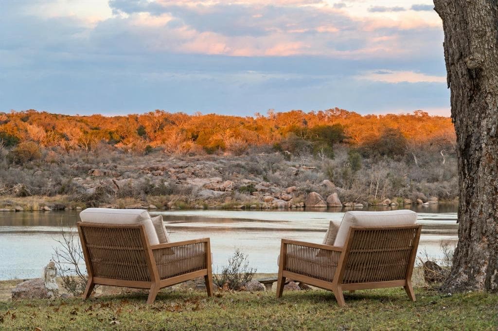 Two chairs on the lawn facing the lake at sunset