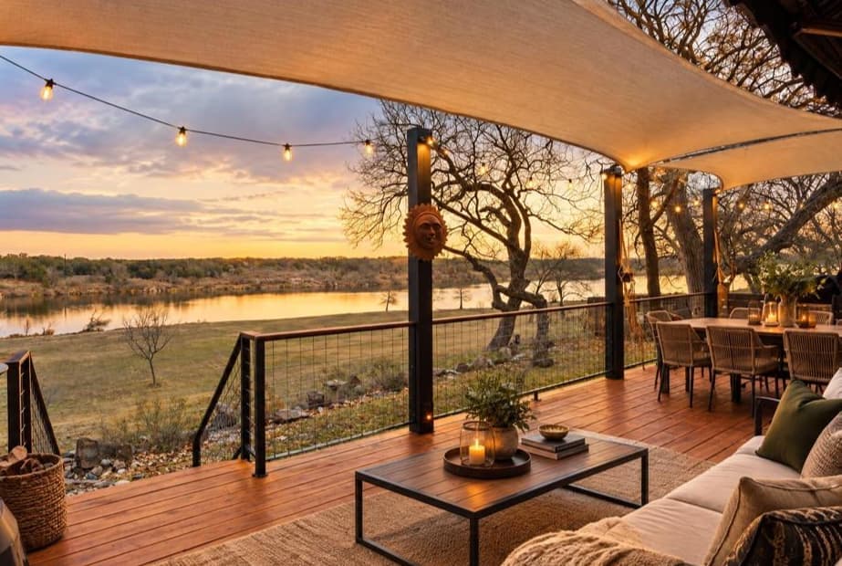 Covered deck at sunset with string lights and a view of the water
