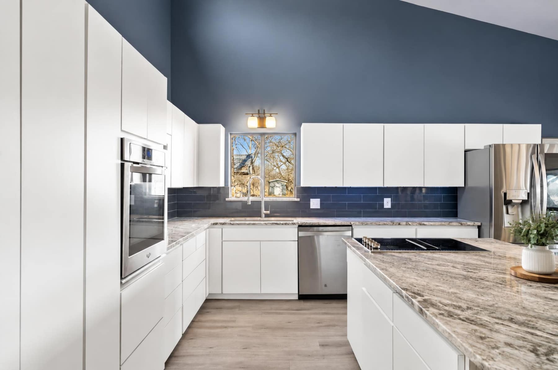 Kitchen with white cabinetry, stone counters, and a window over the sink